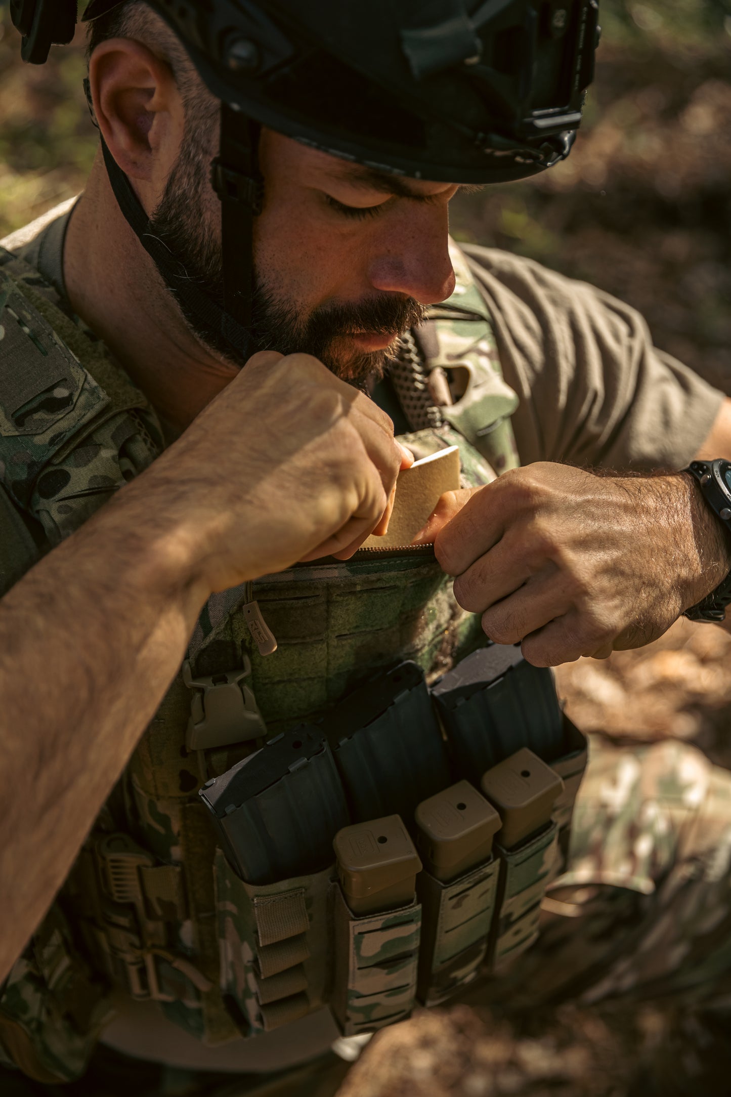 A man opening his plate carrier chest pocket on his Multicam quick release plate carrier.
