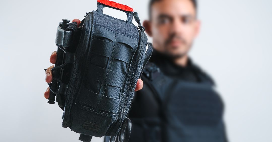 A man holding a black individual first aid kit.