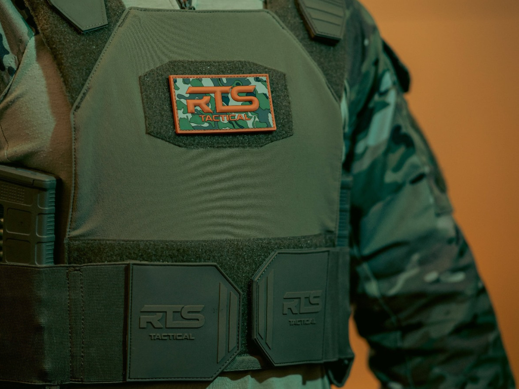 A soft body armor vest in OG Green with an RTS Multicam Velcro patch on the front.