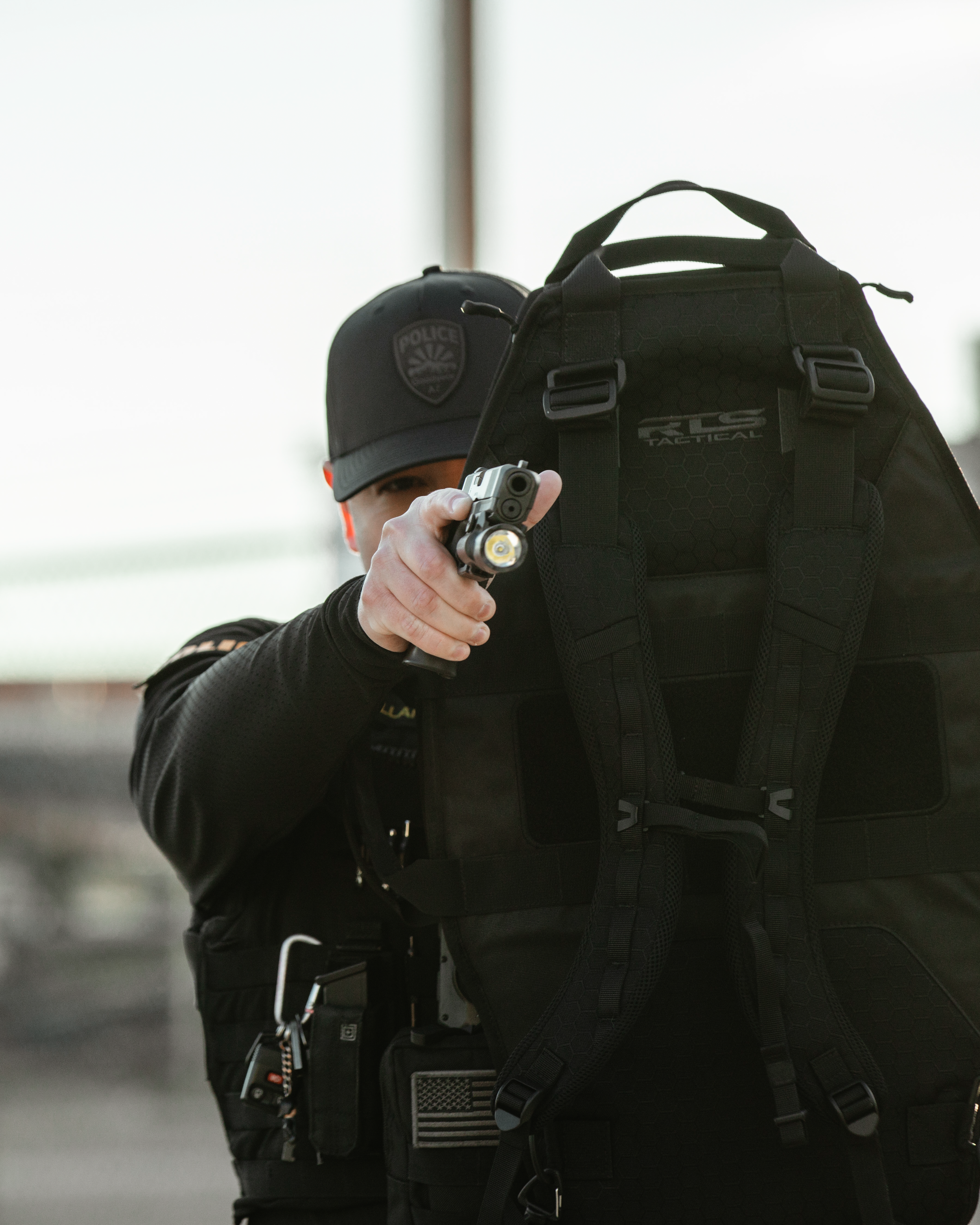 A police officer shielding himself with the mini ballistic shield while holding a gun.